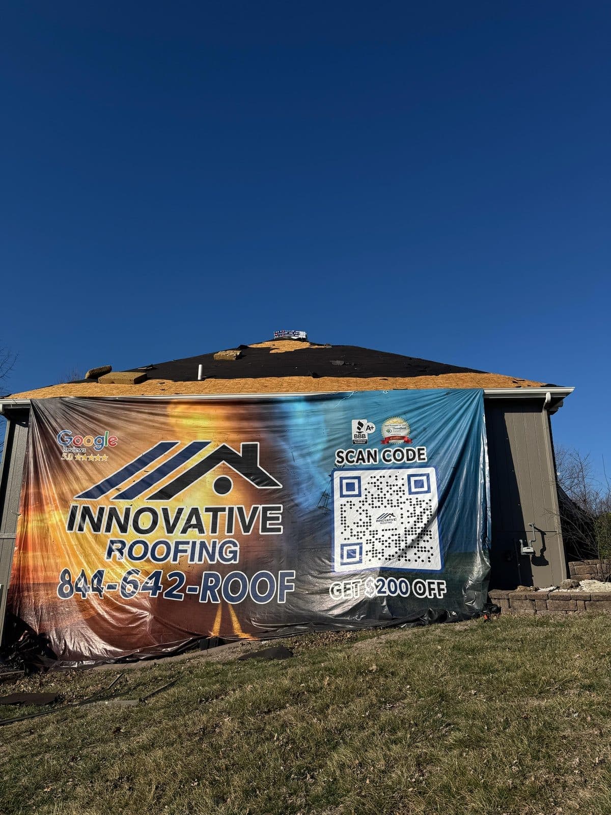Innovative Roofing residential job site mid-install with company banner and roof deck staged for new materials