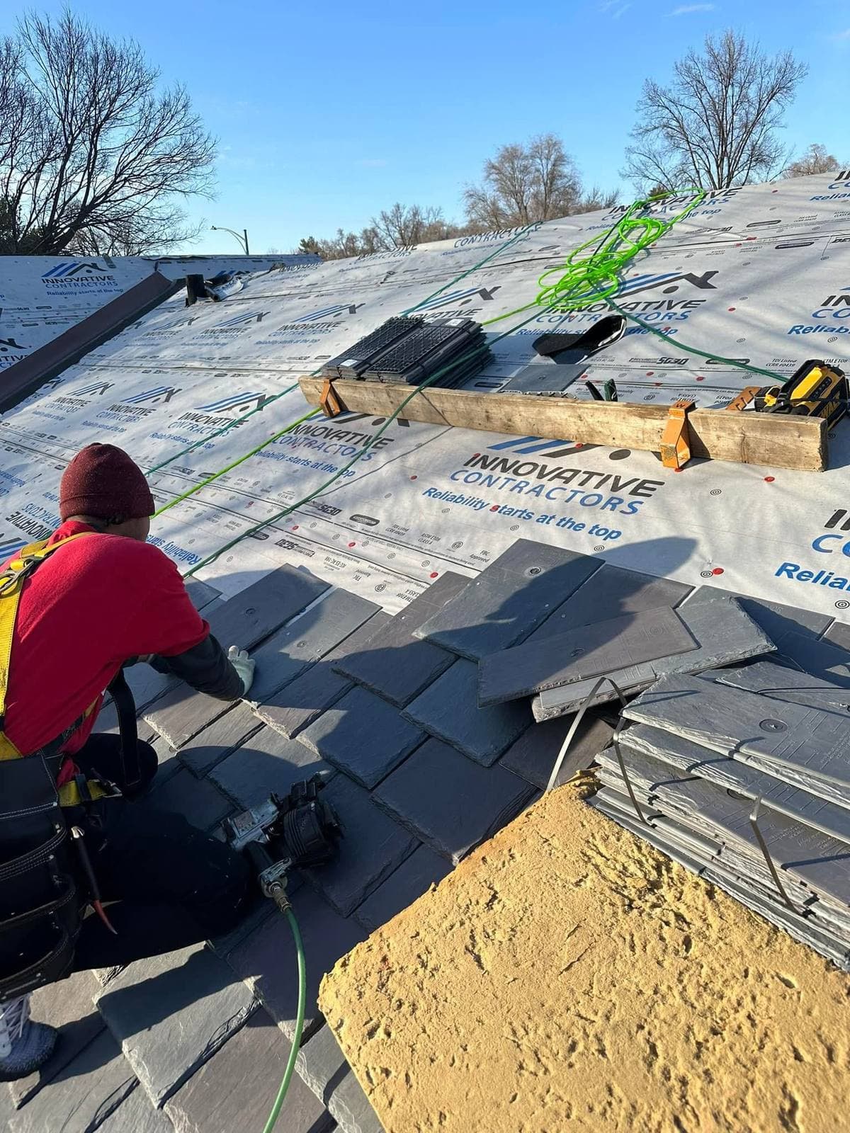 Innovative Roofing installer laying slate-style shingles over new underlayment