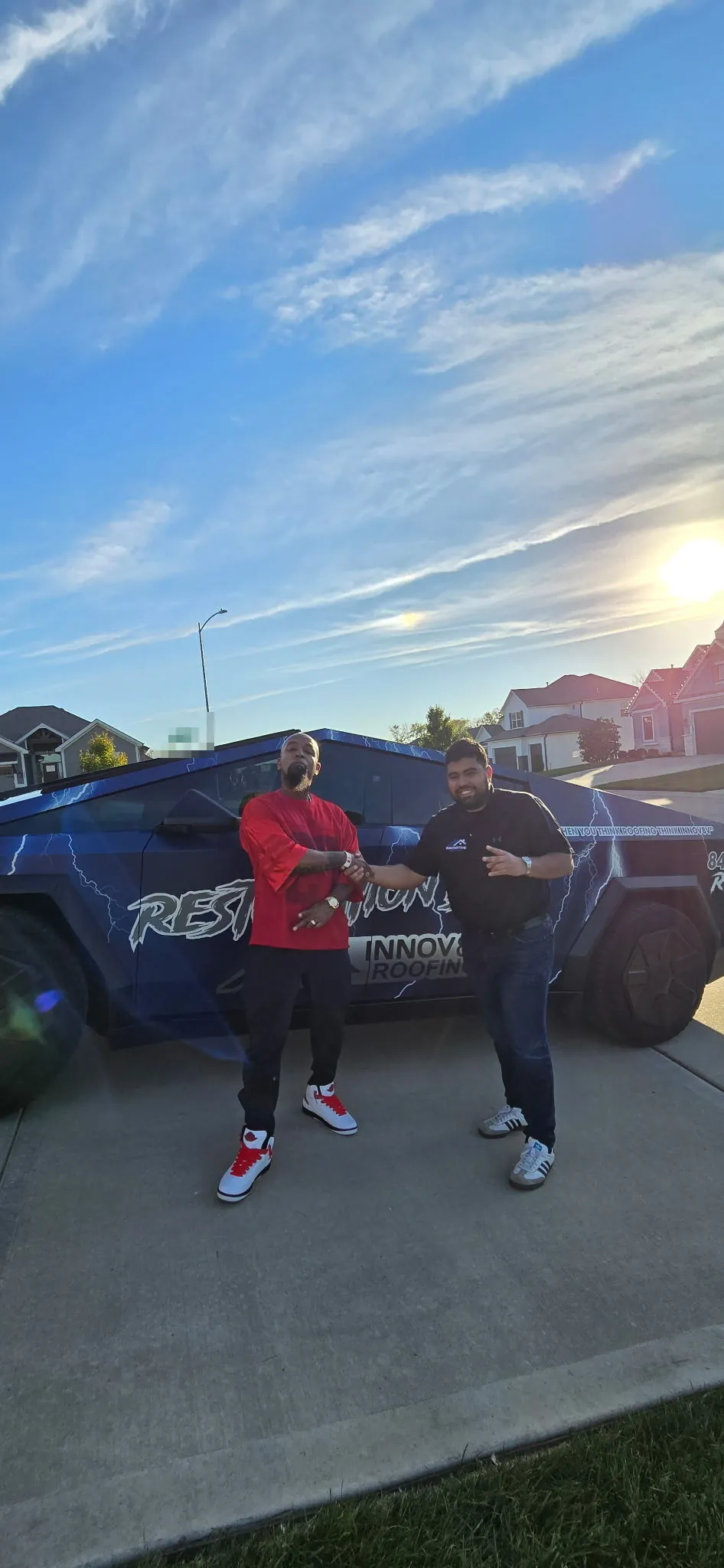 Tech N9ne with an Innovative Roofing team member next to the Innovative Roofing wrapped Cybertruck in a Kansas City neighborhood