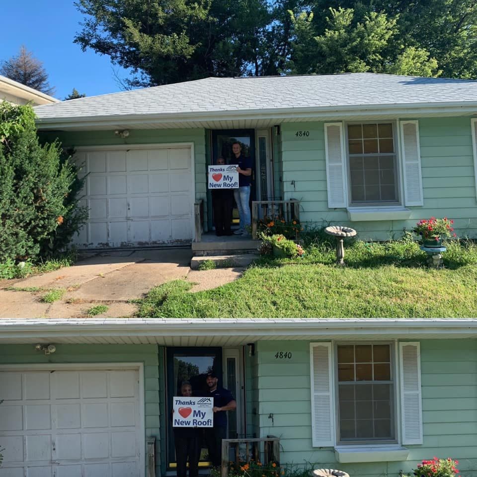 Homeowner and Innovative Roofing team member holding a thank-you sign on the porch of a green ranch with a new gray roof