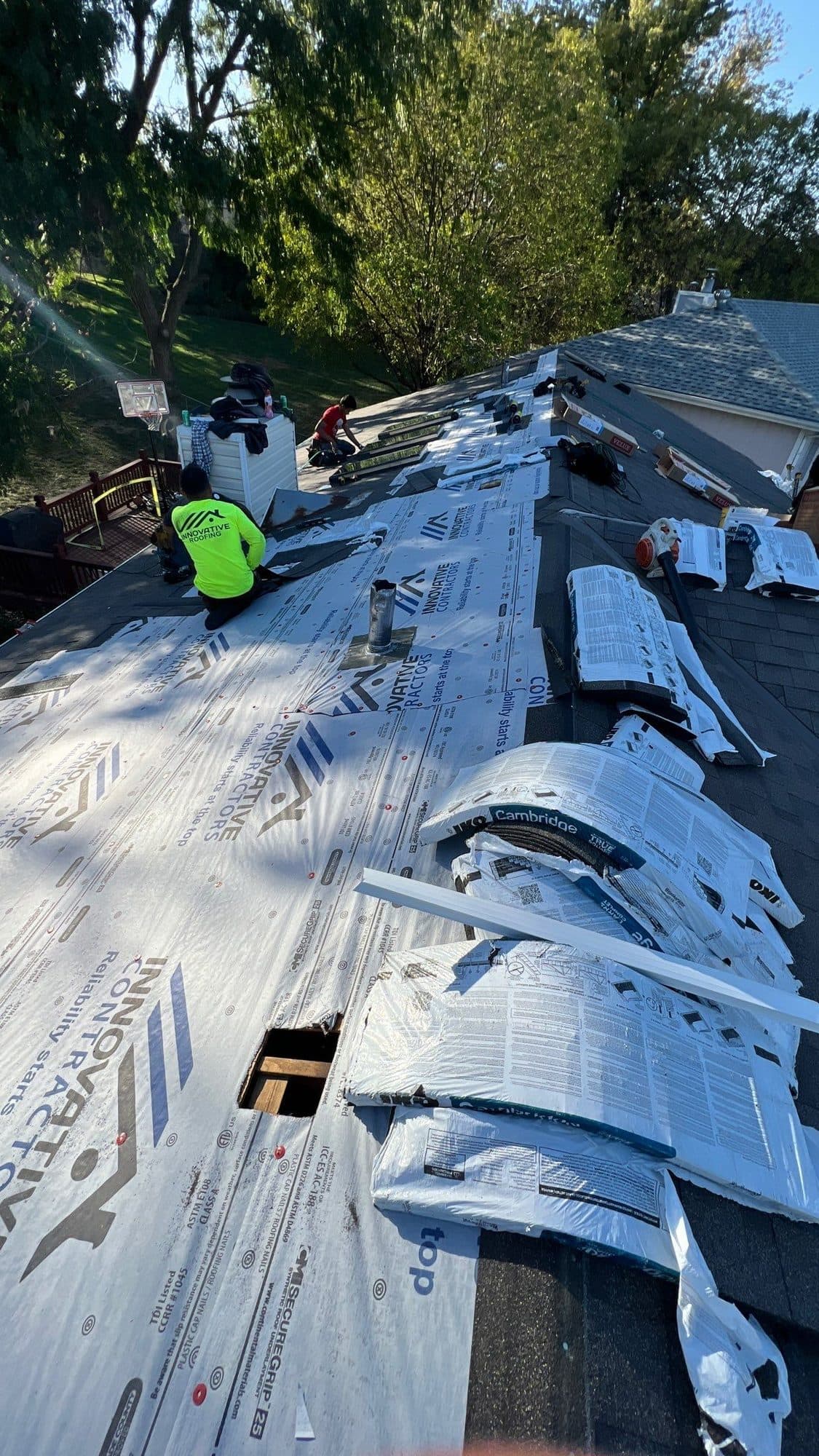 Roofer installing new underlayment on a steep roof slope