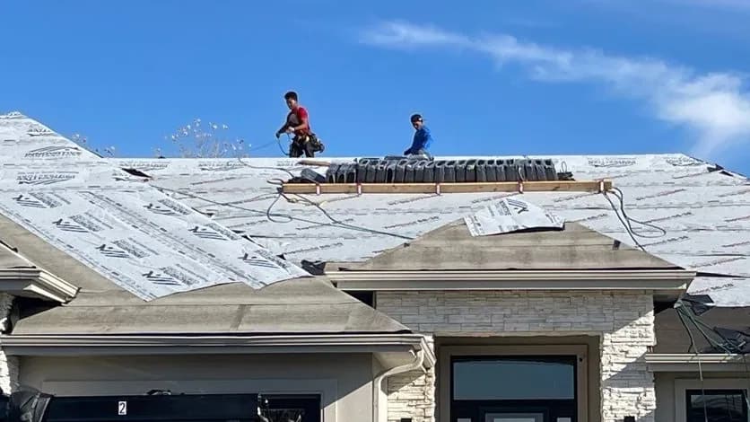 Innovative Roofing crew on an Omaha-area roof replacement, with new synthetic underlayment down and shingle bundles staged on the ridge