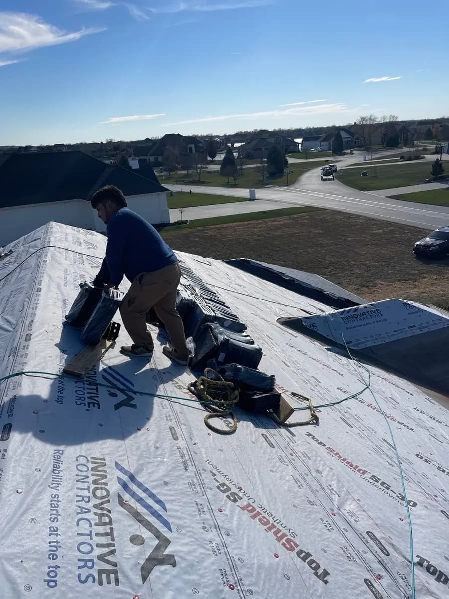 Innovative Roofing installer laying new underlayment on an Omaha-area roof