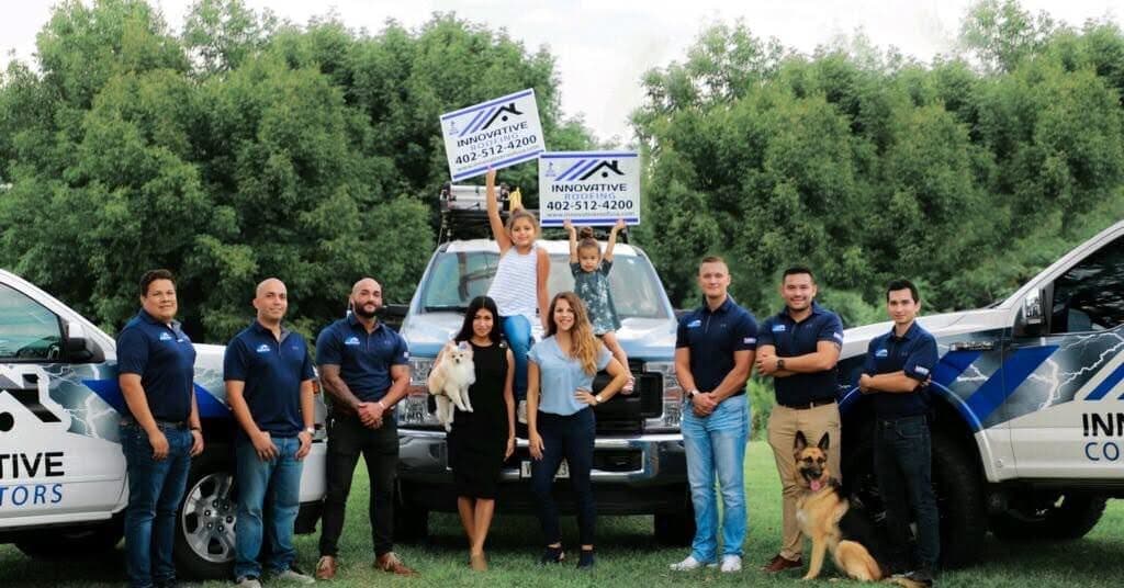 Innovative Roofing crew posing with branded service trucks ready for residential exterior work