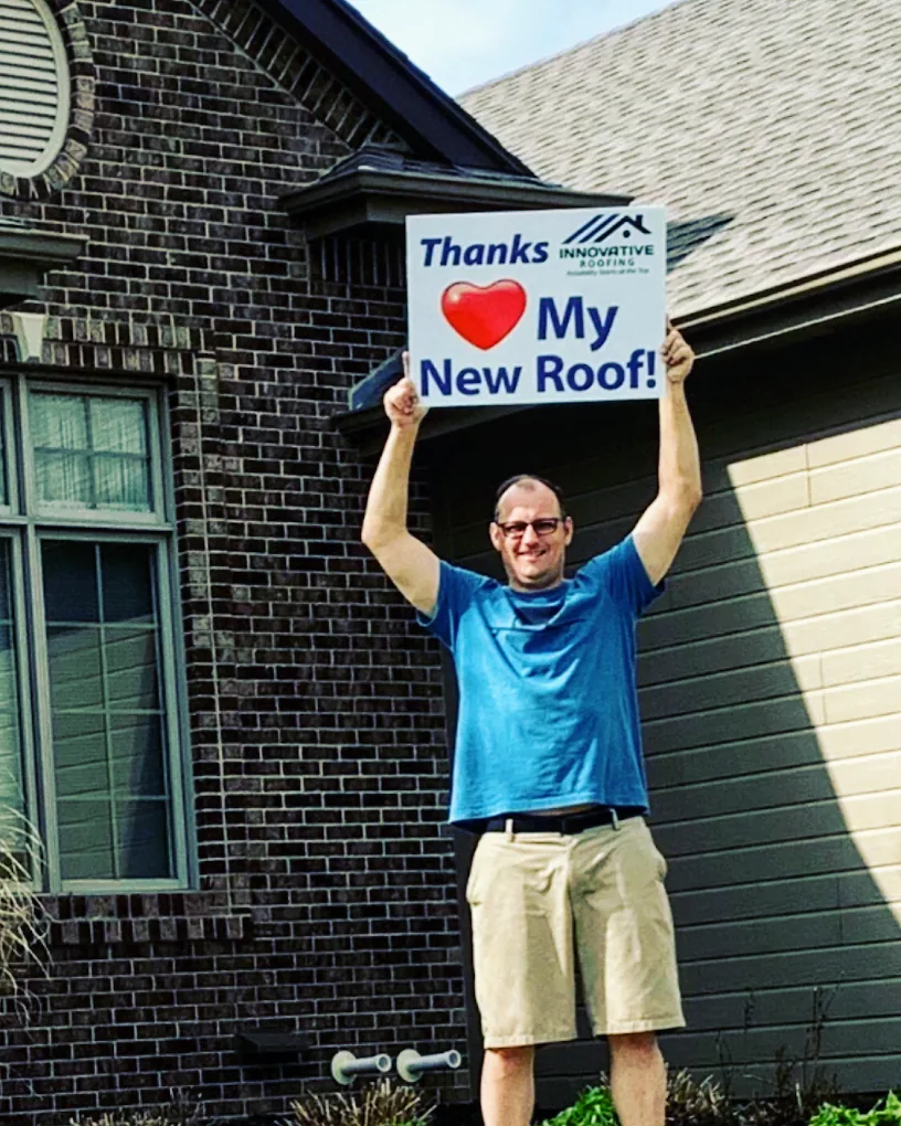 Omaha homeowner holding his new roof sign